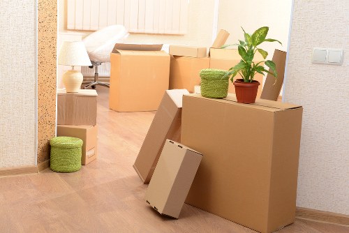 Professional movers carrying a sofa through a residential property in Holland Park